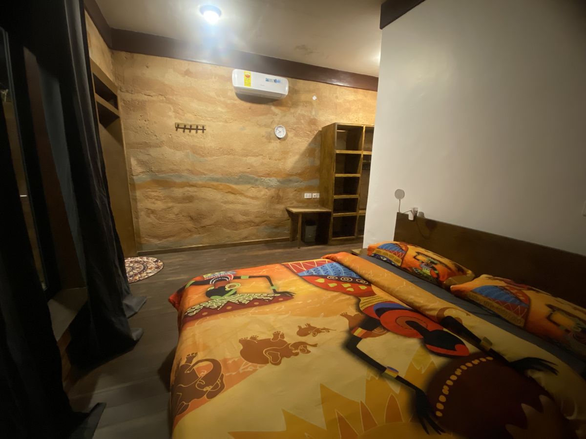 Kente bedding against the rammed-earth wall
